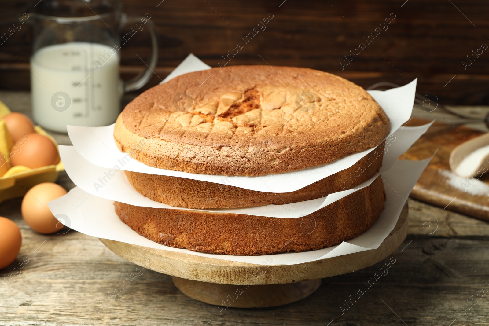 Photo of Tasty cut sponge cake and ingredients on wooden table