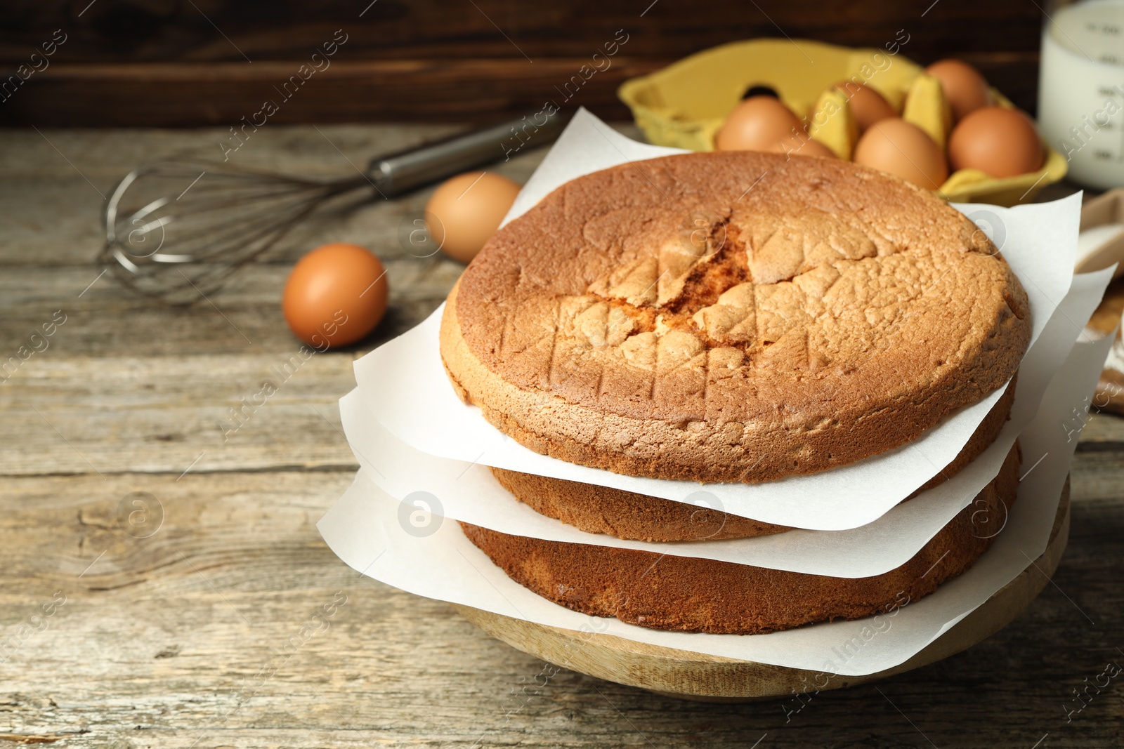 Photo of Tasty cut sponge cake and ingredients on wooden table