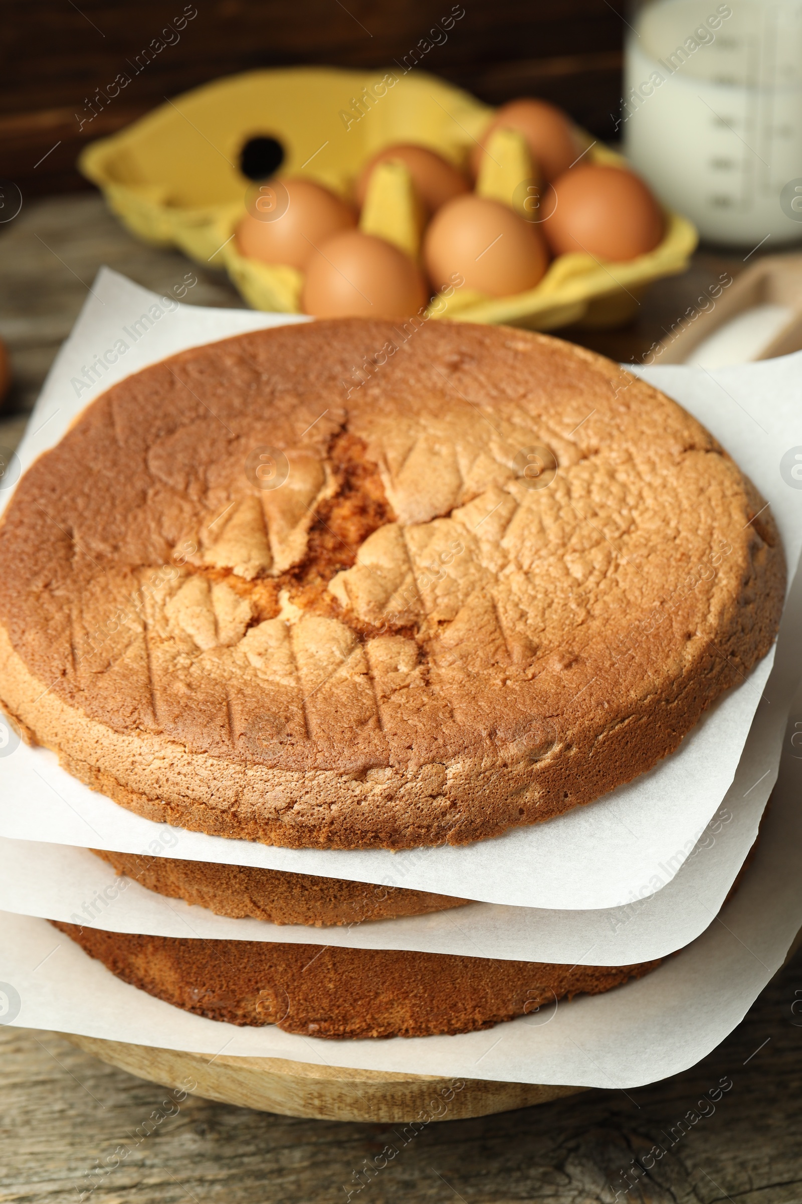 Photo of Tasty cut sponge cake and ingredients on wooden table