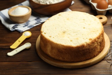 Photo of Tasty cut sponge cake and ingredients on wooden table