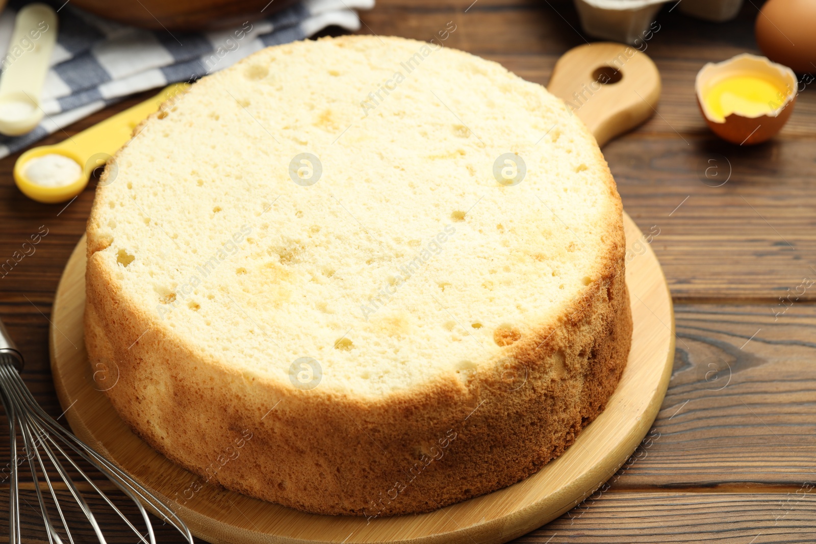 Photo of Tasty cut sponge cake and ingredients on wooden table