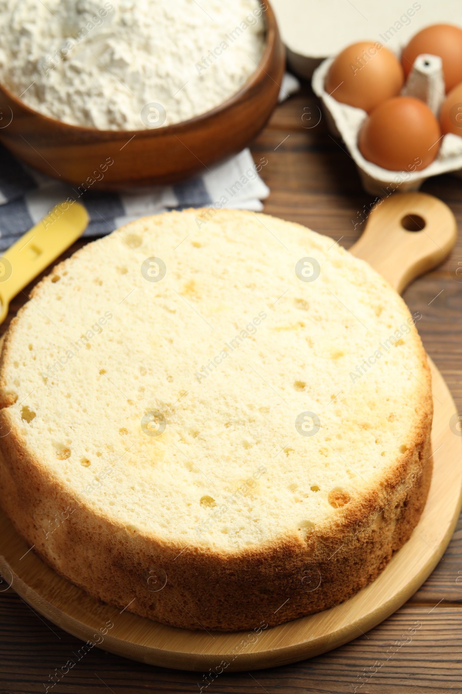 Photo of Tasty cut sponge cake and ingredients on wooden table