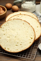 Photo of Tasty cut sponge cake and ingredients on wooden table