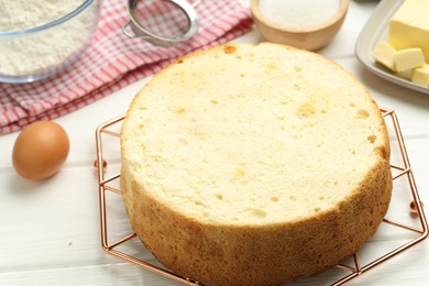 Photo of Tasty sponge cake and ingredients on white wooden table