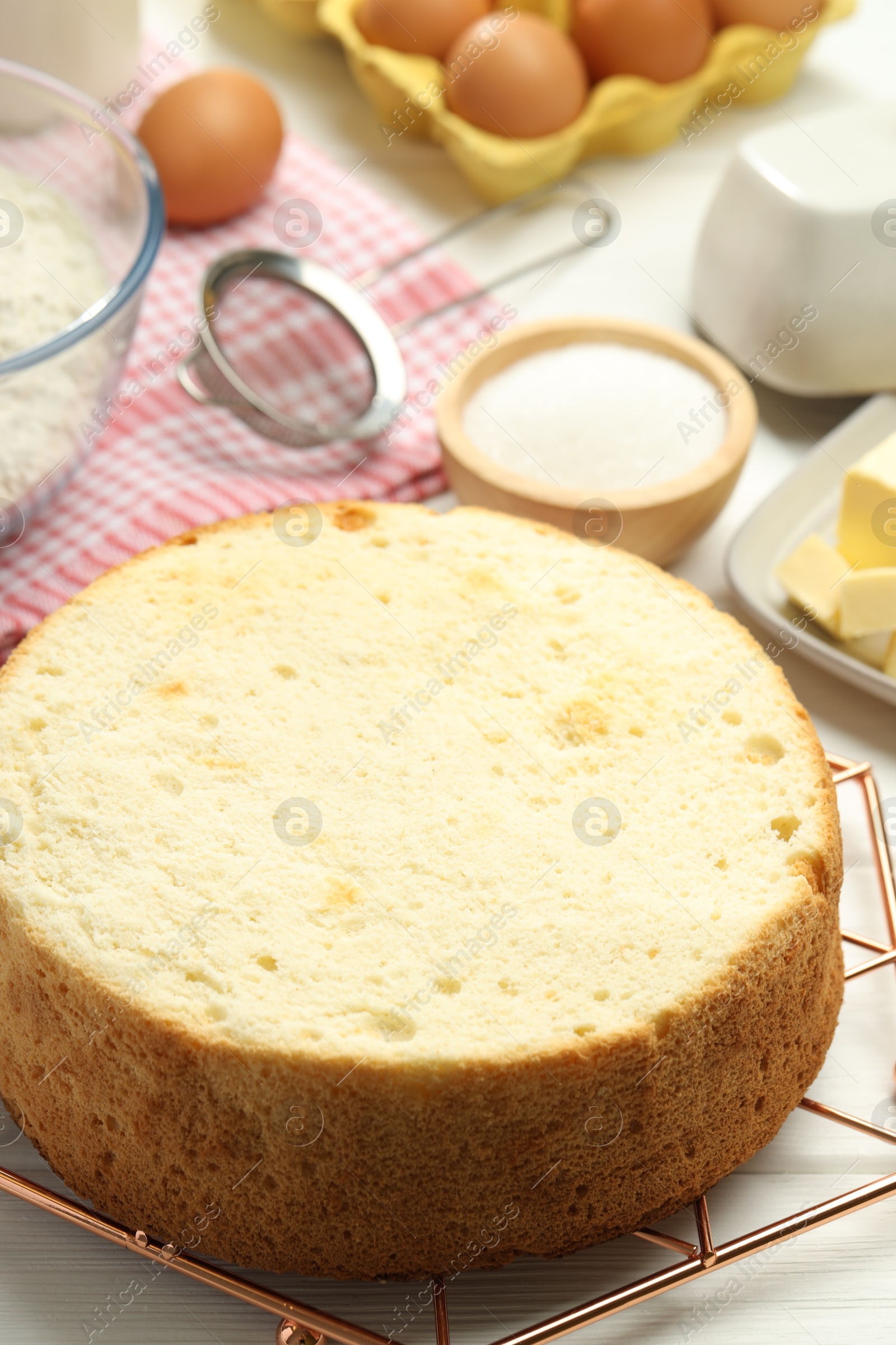 Photo of Tasty sponge cake and ingredients on white wooden table