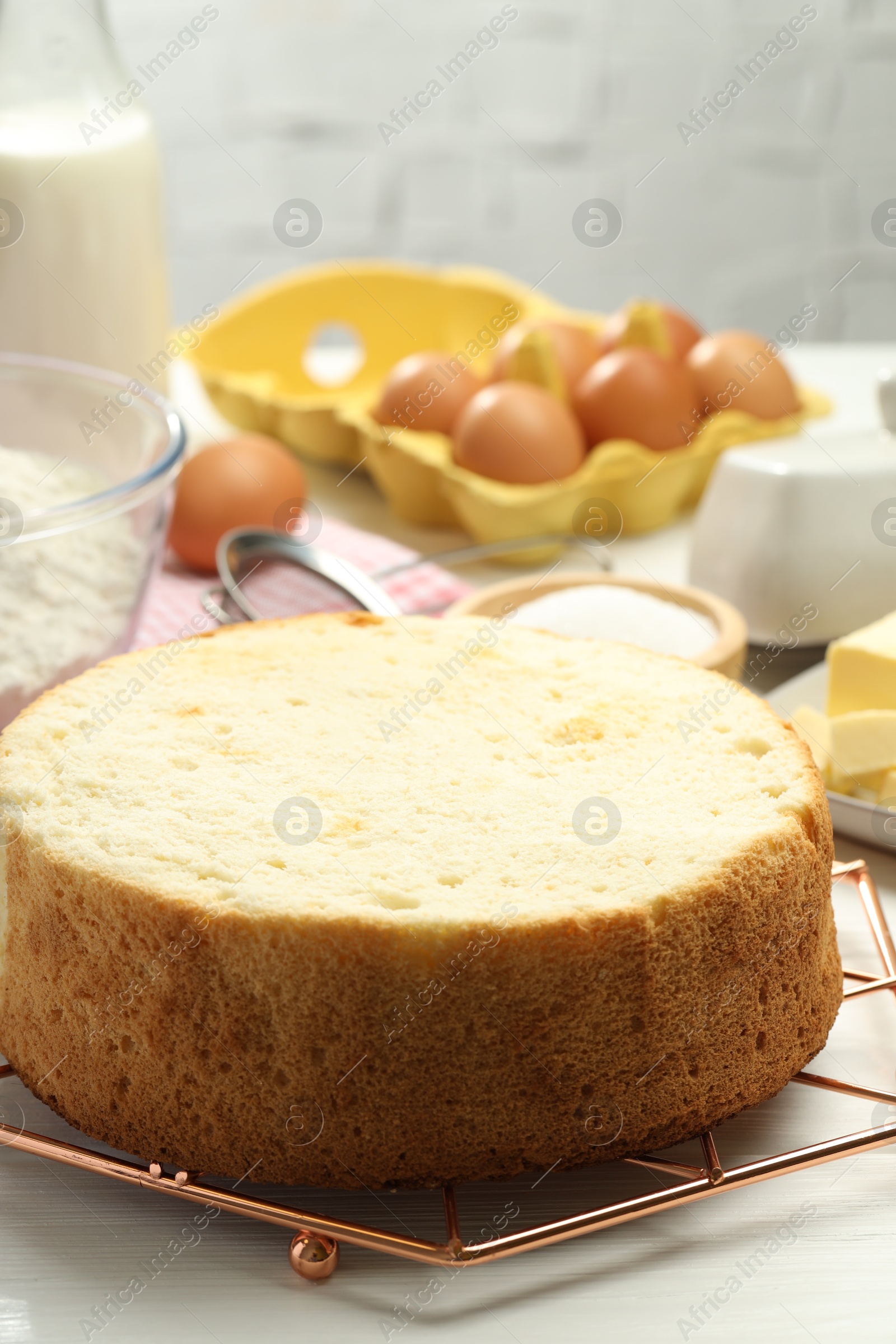 Photo of Tasty sponge cake and ingredients on white wooden table