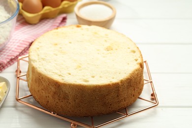 Photo of Tasty sponge cake and ingredients on white wooden table