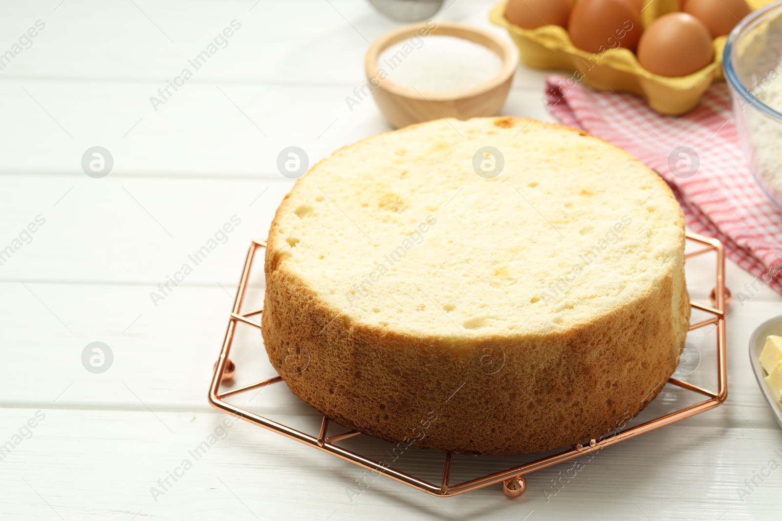 Photo of Tasty sponge cake and ingredients on white wooden table