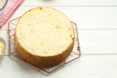 Photo of Tasty cut sponge cake on white wooden table, above view. Space for text