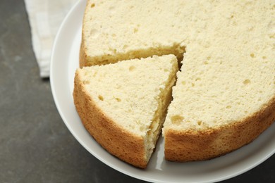 Photo of Tasty cut sponge cake on grey table, closeup