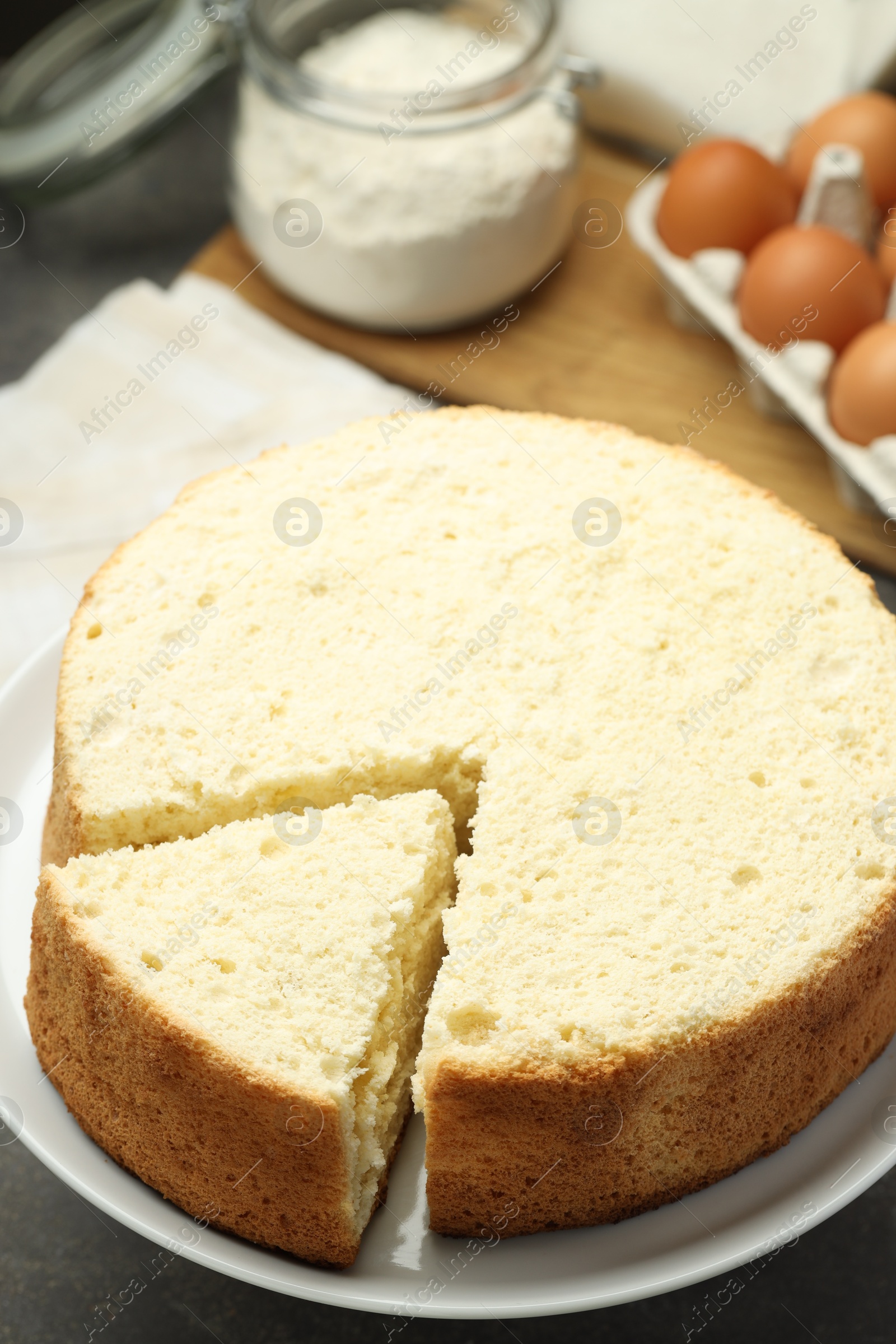 Photo of Tasty cut sponge cake on grey table