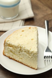 Photo of Piece of delicious sponge cake and fork on wooden table, closeup