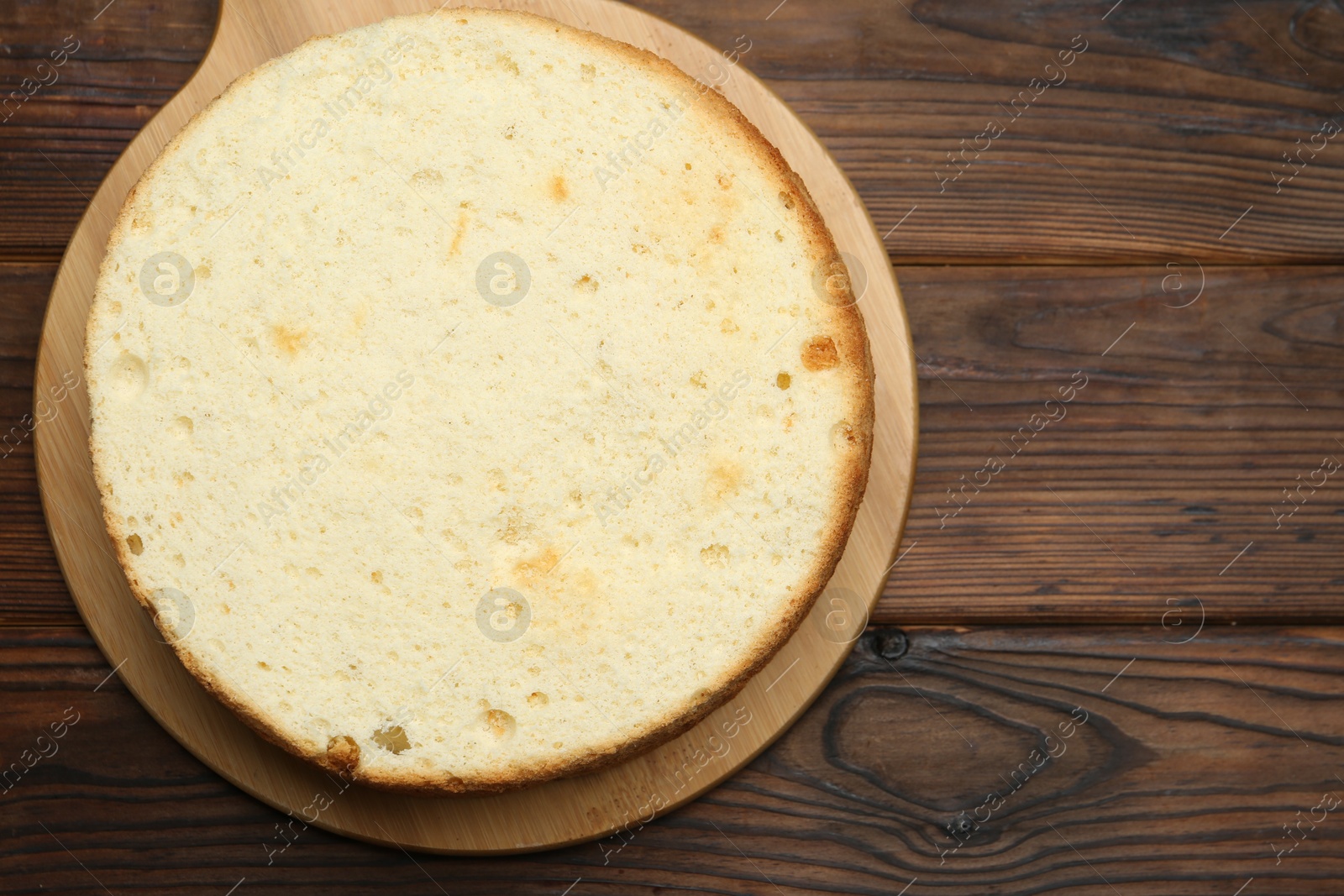 Photo of Delicious cut sponge cake on wooden table, top view. Space for text