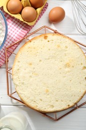 Photo of Delicious cut sponge cake and ingredients on white wooden table, flat lay