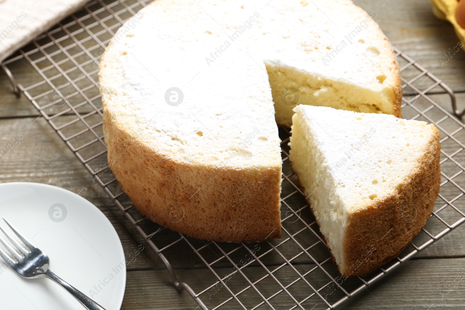 Photo of Delicious cut sponge cake and fork on wooden table