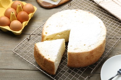 Delicious cut sponge cake and ingredients on wooden table