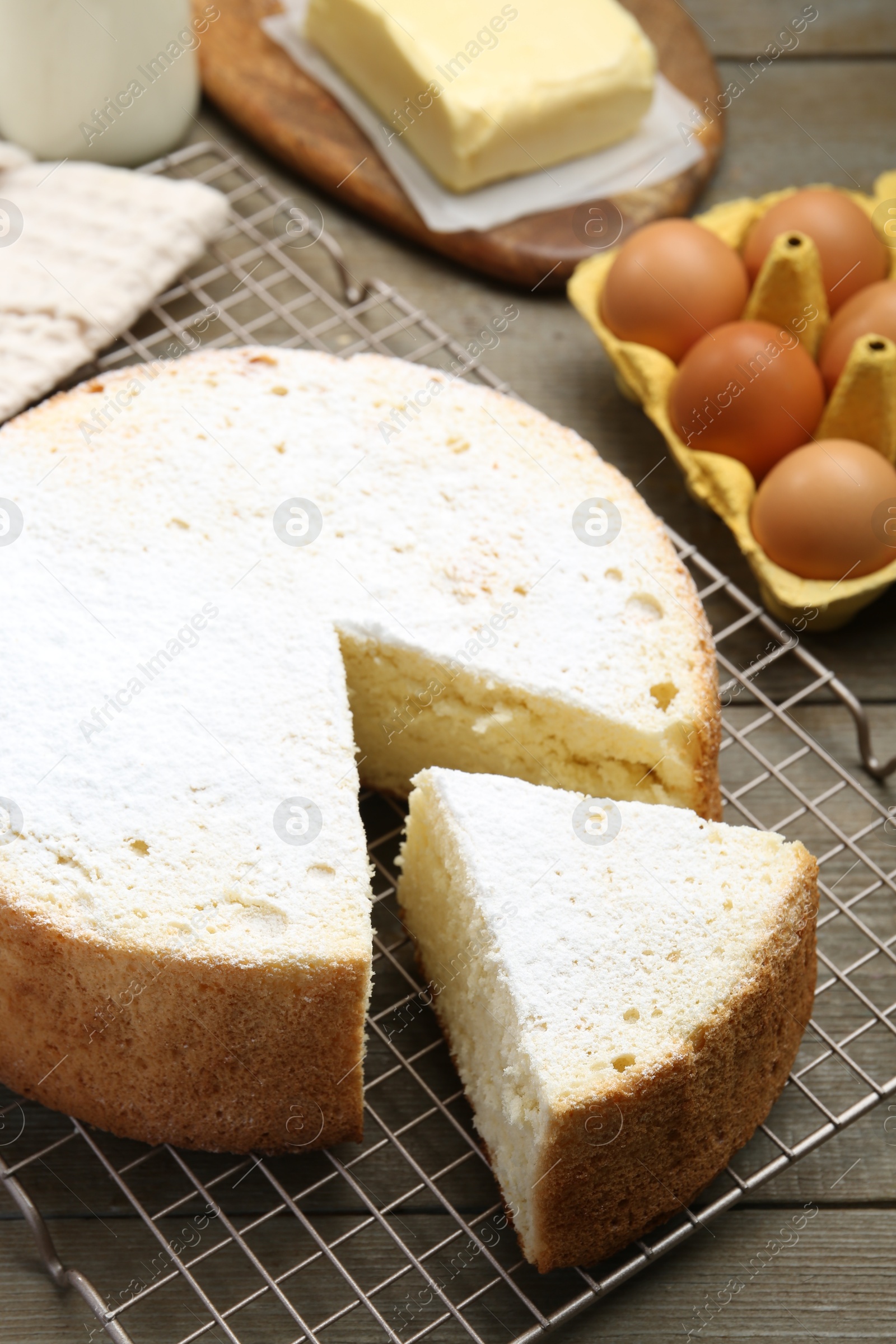 Photo of Delicious cut sponge cake and ingredients on wooden table