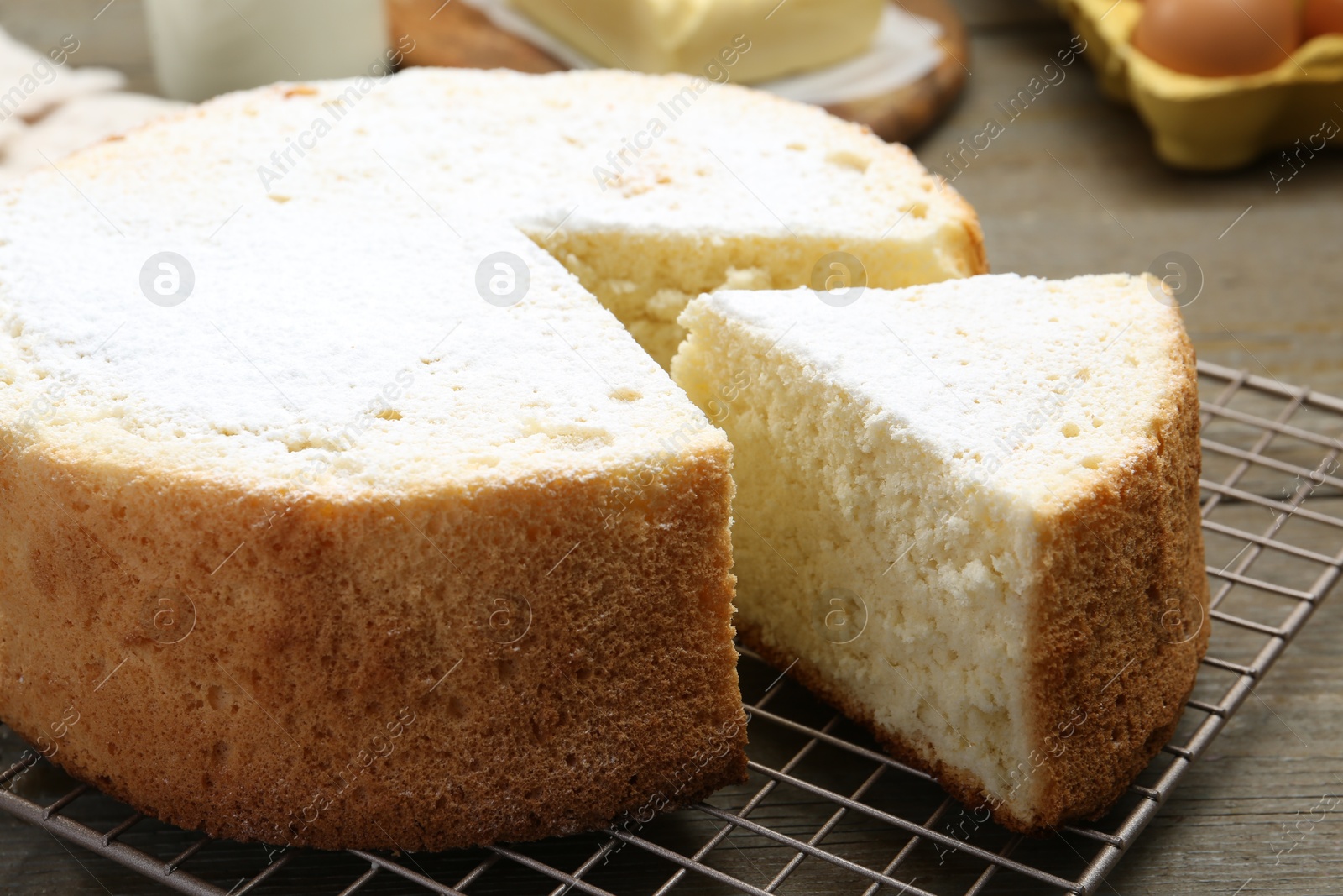 Photo of Delicious cut sponge cake with powdered sugar on wooden table, closeup