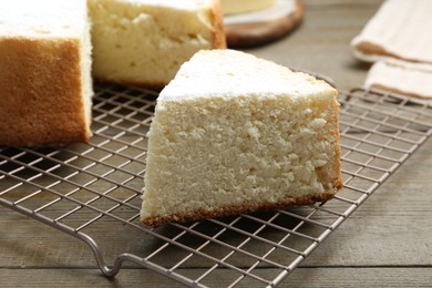 Photo of Delicious cut sponge cake with powdered sugar on wooden table, closeup