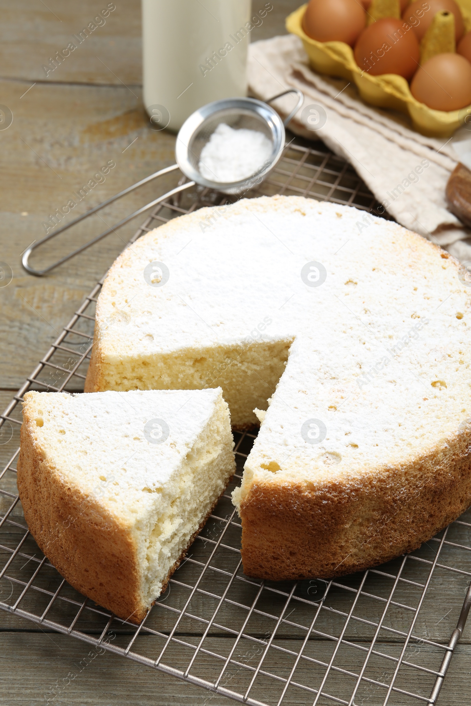 Photo of Delicious cut sponge cake and ingredients on wooden table