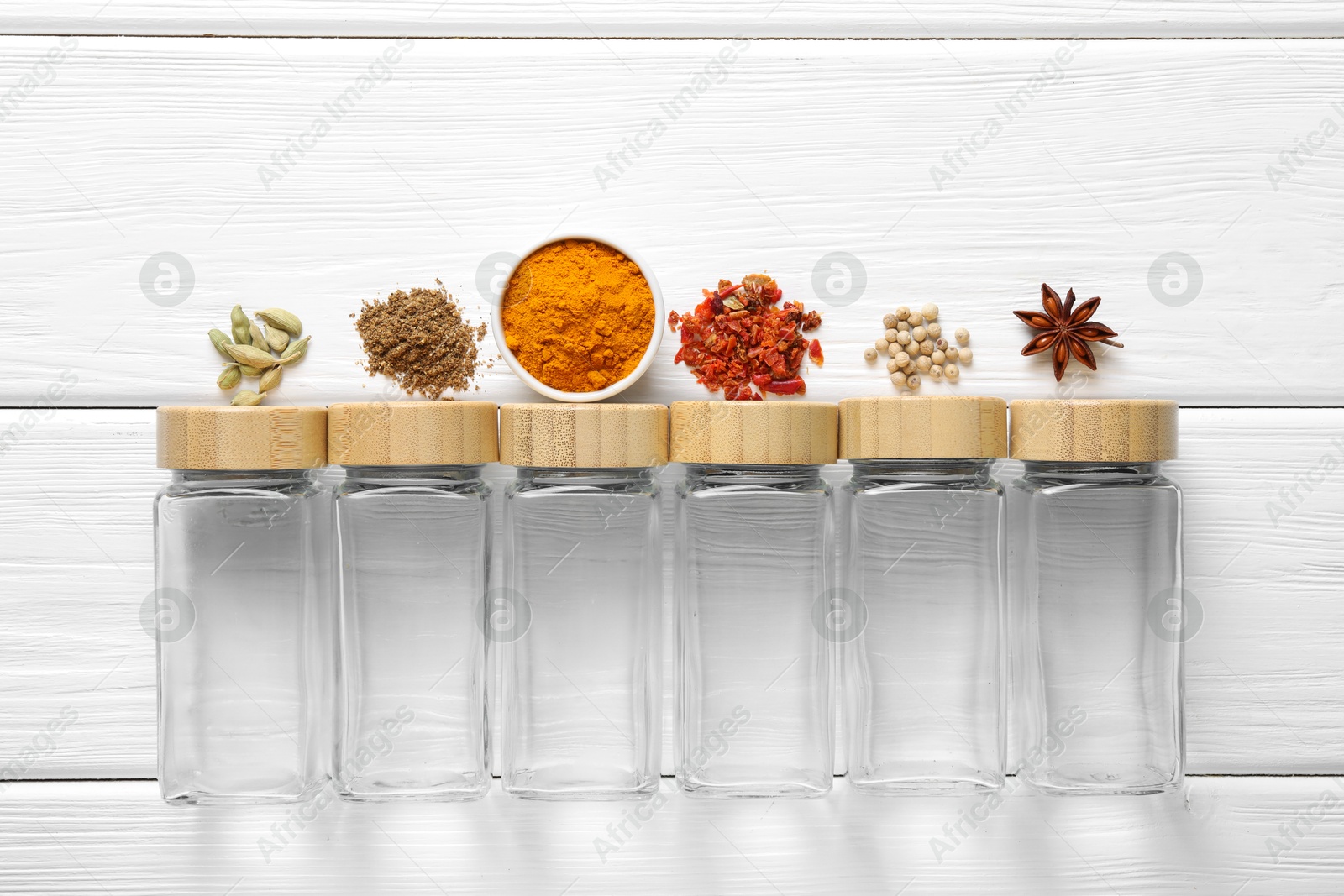 Photo of Different spices and glass jars on white wooden table, top view