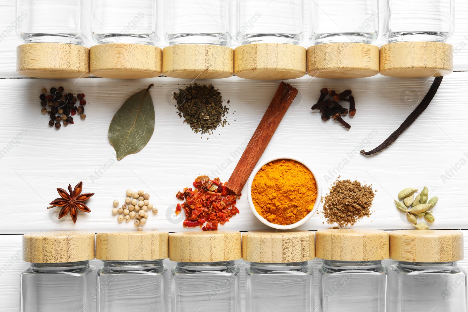 Photo of Different spices and glass jars on white wooden table, top view