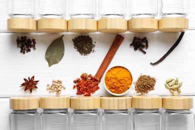 Photo of Different spices and glass jars on white wooden table, top view