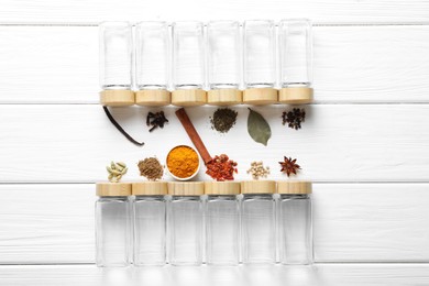 Photo of Different spices and glass jars on white wooden table, top view