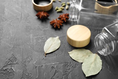 Photo of Different spices and glass jars on black table, space for text