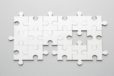 Photo of White puzzle pieces on grey background, top view