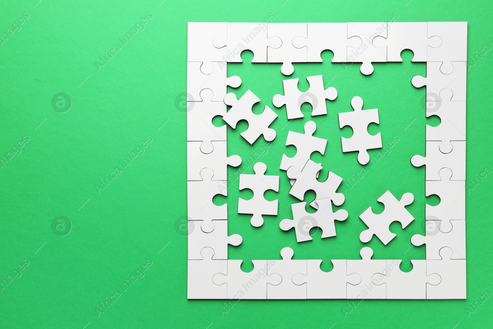 Photo of White puzzle pieces on green background, top view