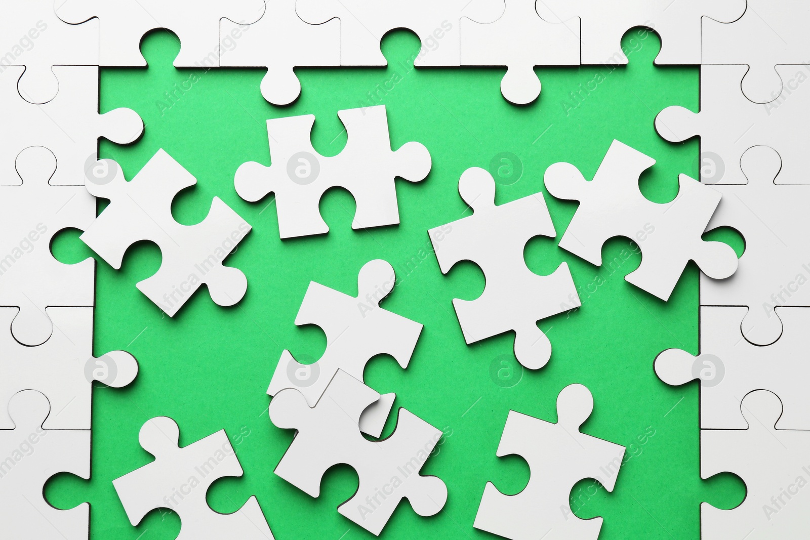 Photo of White puzzle pieces on green background, top view