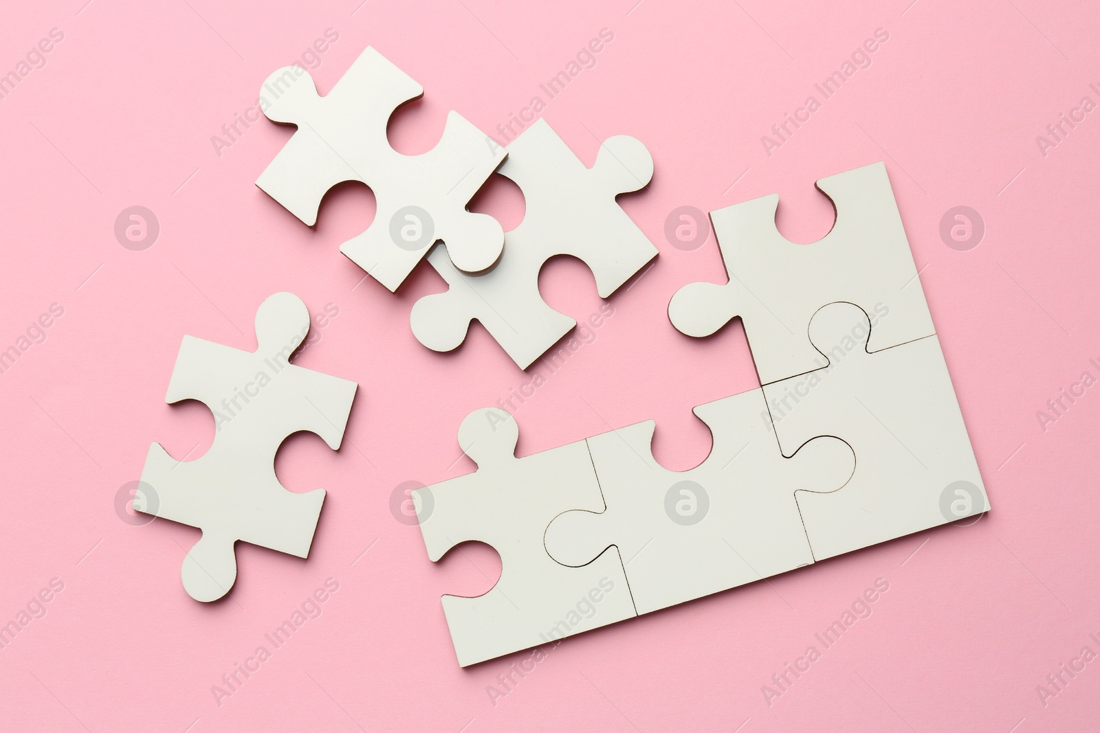 Photo of White puzzle pieces on pink background, top view