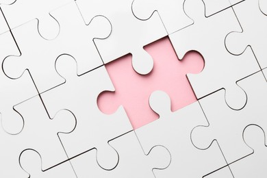 Photo of White puzzle with missing piece on pink background, top view