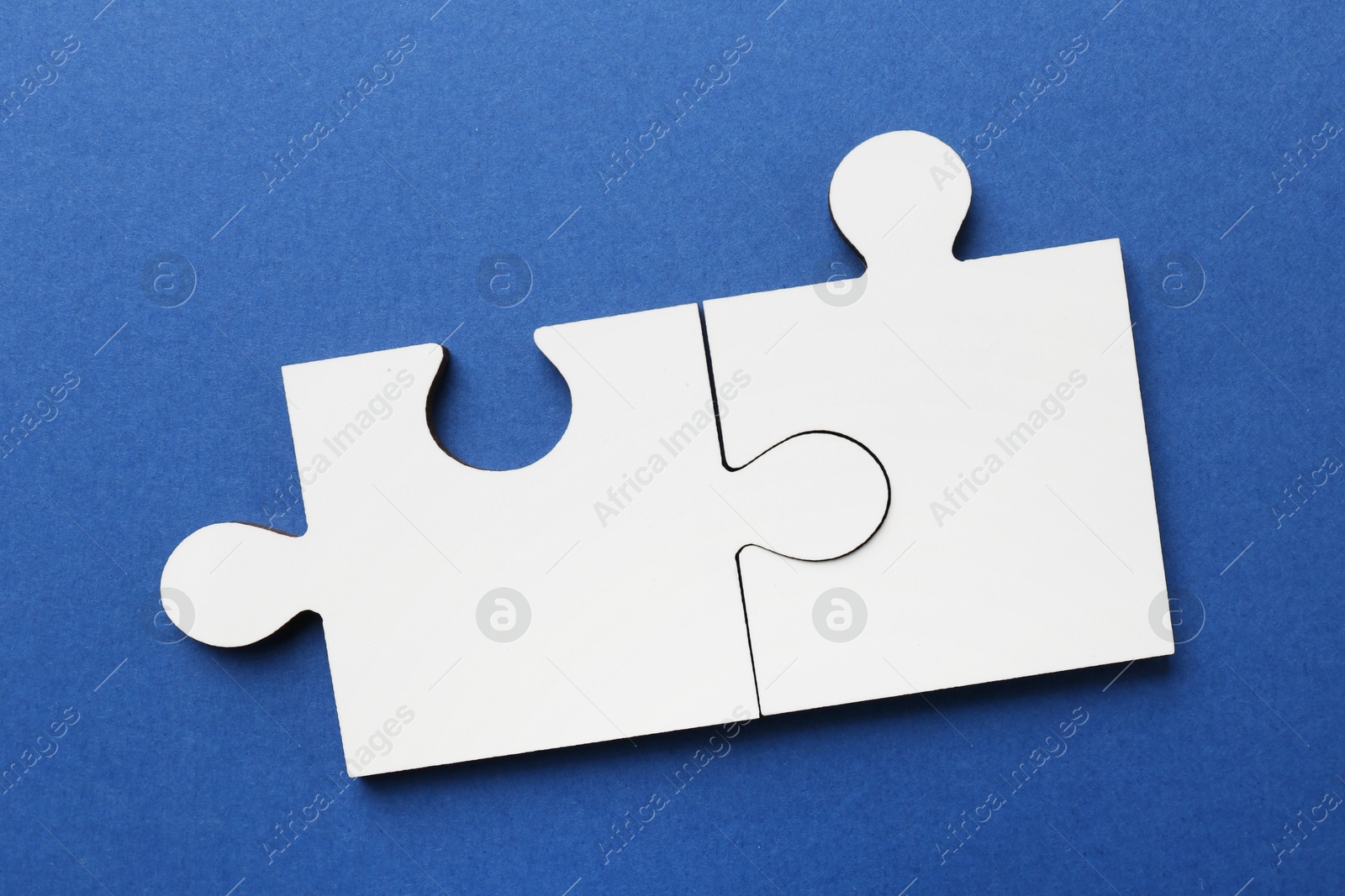 Photo of White puzzle pieces on blue background, top view