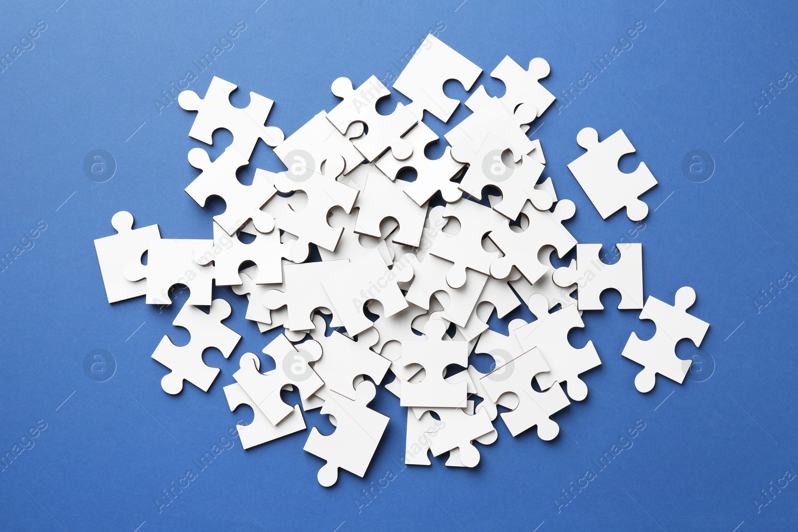 Photo of White puzzle pieces on blue background, top view