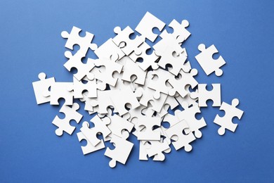 White puzzle pieces on blue background, top view