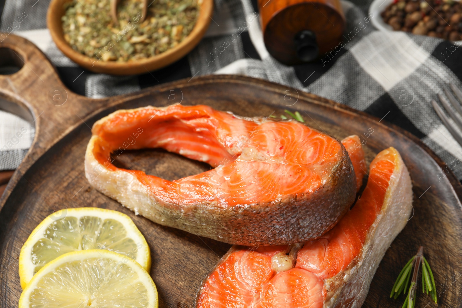 Photo of Tasty grilled salmon steaks, lemon and spices on table, closeup