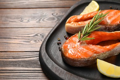 Photo of Tasty grilled salmon steaks, lemon and spices on wooden table, closeup. Space for text