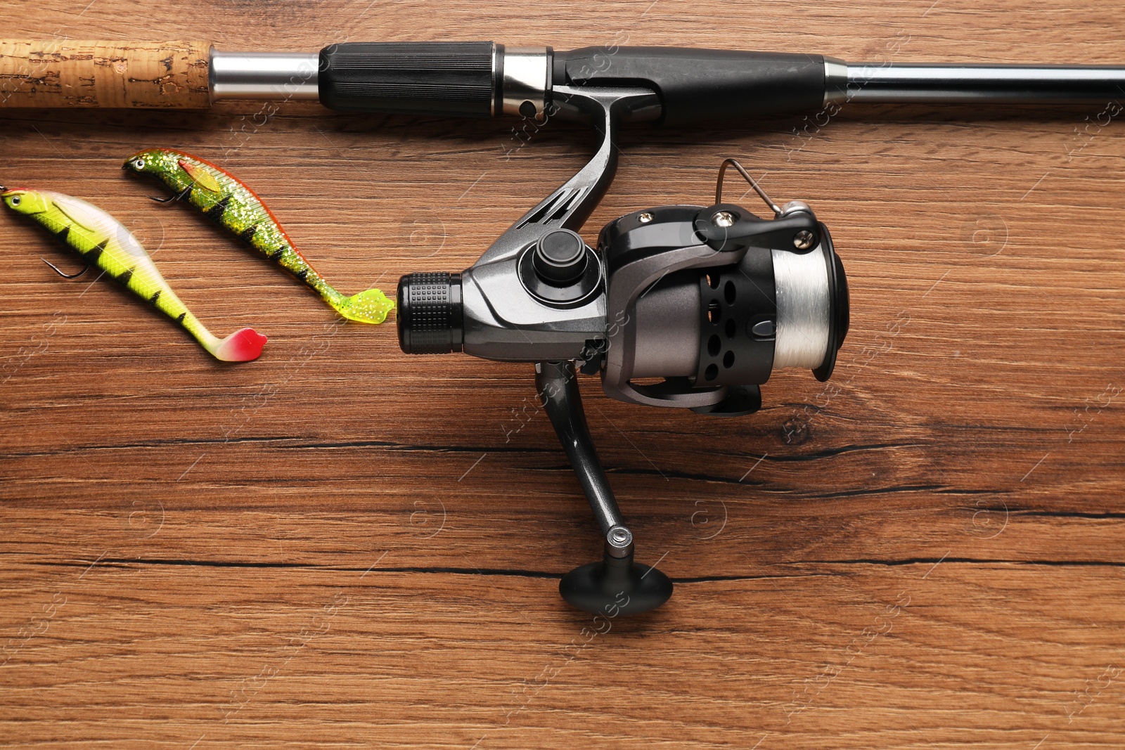 Photo of Fishing rod with spinning reel and baits on wooden table