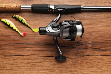 Fishing rod with spinning reel and baits on wooden table