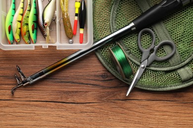 Fishing rod, baits, line, scissors, floats and net on wooden table, top view