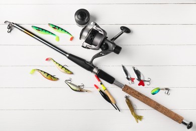 Photo of Fishing rod with spinning reel, baits and floats on white wooden table, flat lay