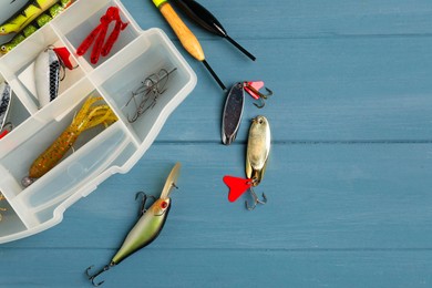 Different fishing baits, hooks and floats on blue wooden table, top view. Space for text