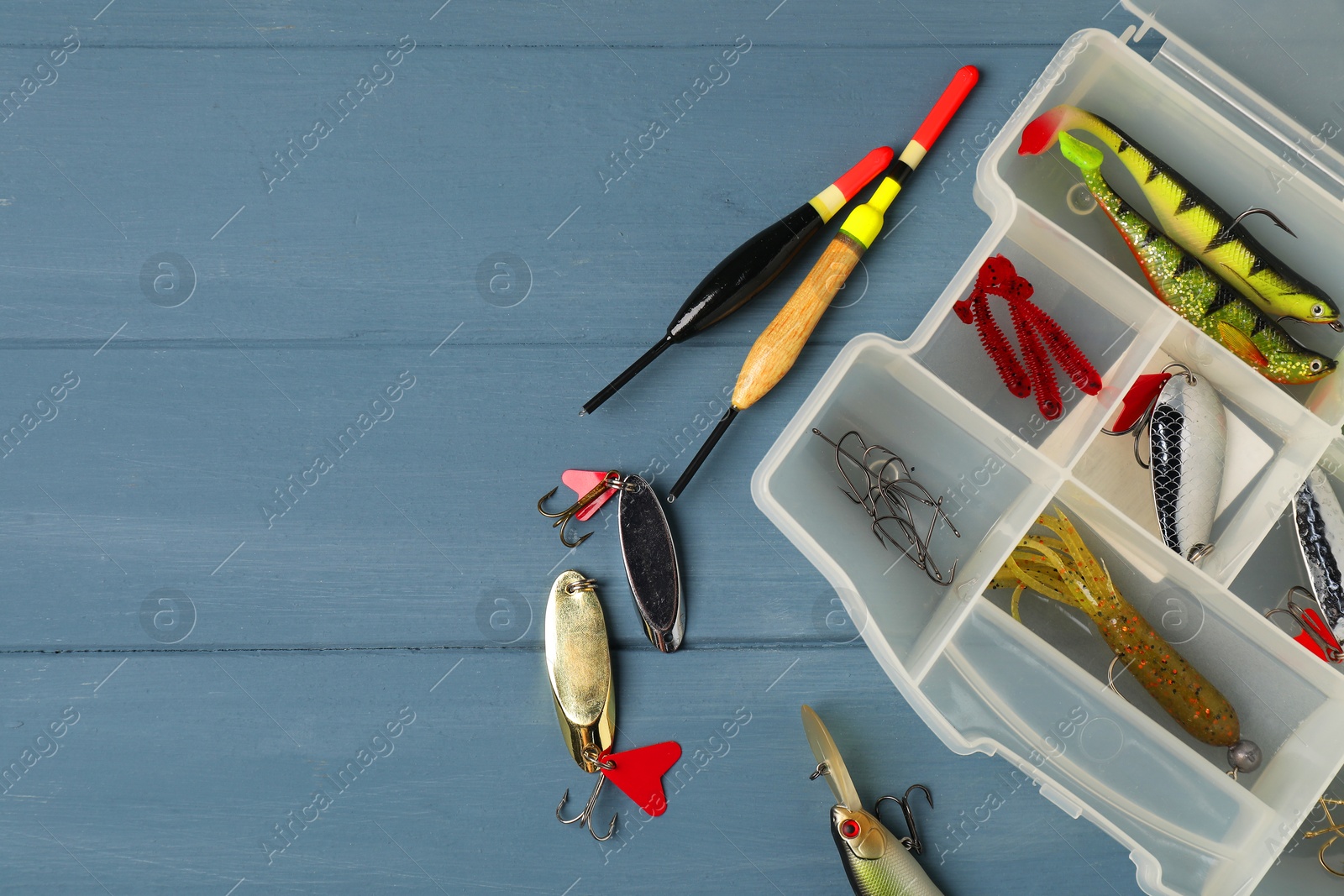 Photo of Different fishing baits, hooks and floats on blue wooden table, top view. Space for text