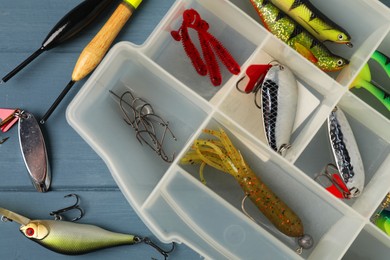 Different fishing baits, hooks and floats on blue wooden table, top view