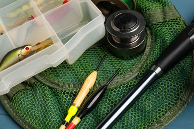 Fishing rod, spinning reel, floats, net and baits on blue table