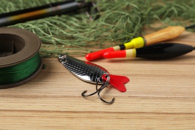 Photo of Fishing bait, floats, net and line on wooden table, closeup