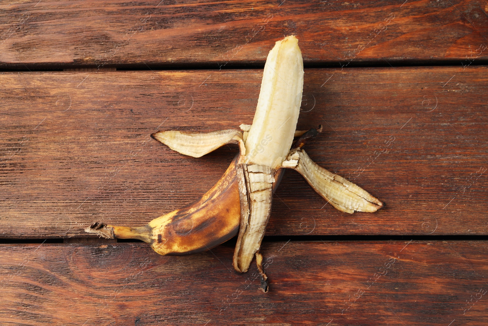 Photo of Overripe banana with dark spots on wooden table, top view