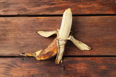 Overripe banana with dark spots on wooden table, top view